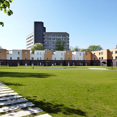 Wohn- und Gewerbekomplex in Duesseldorf von aussen mit Fokus auf die grosse gruene Wiese und den Gewegsteinen