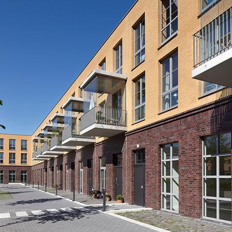 Wohn- und Gewerbekomplex in Duesseldorf von aussen mit Bolkonen, Eingaengen, Gehwegen und hellbrauner und dunkelbrauner Klinkerfassade