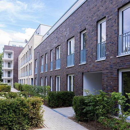 Wohnungsgebaeude in Bocholt am Fluss mit Klinkerfassade, Buschen und Fussweg