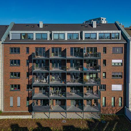 Ein Gebaeude des Wohnkomplexes Moll in Duesseldorf im Fokus mit brauner Klinkerfassade und Balkonen