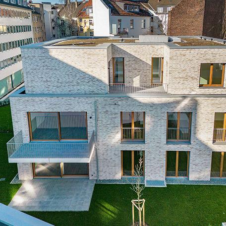 Frontalvogelperspektive des Gebaeude im Hinterhof des Wohnkomplexes Moll in Duesseldorf mit beiger Klinkerfassade, Balkonen, Terrassen und Gaerten