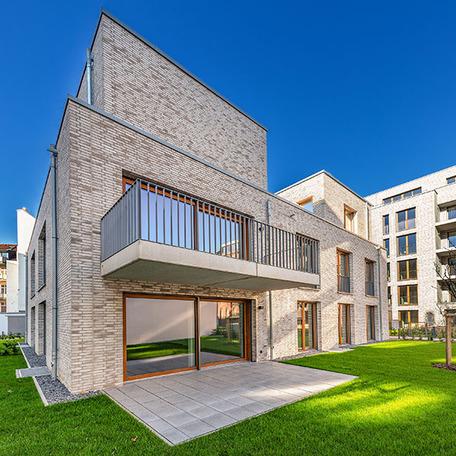 Das Gebaeude im Hinterhof des Wohnkomplexes Moll in Duesseldorf im Fokus mit beiger Klinkerfassade, Balkonen, Terrassen und Gaerten