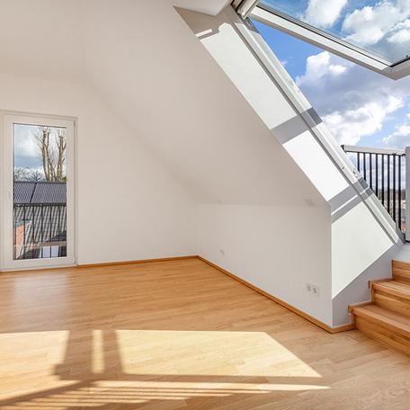 Zimmer einer Wohnung des Wohnquatiers in Angermund mit weissen Waenden, Holzboden, grossem Kippfenster mit Tuer und Treppe zum Balkon