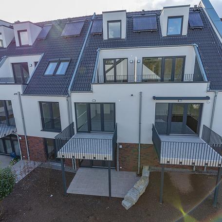 Haeuserreihe des Wohnquatiers in Angermund von aussen mit beiger Fassade, Terassen, Gaerten und Balkonen