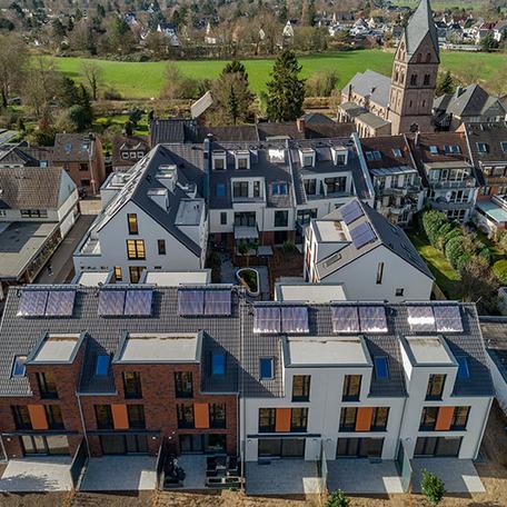 Drohnenansicht der Haeuserreihen des Wohnquatiers in Angermund von aussen mit beiger oder brauner Klinkerfassade und orangen Akzenten, Terassen und Gaerten