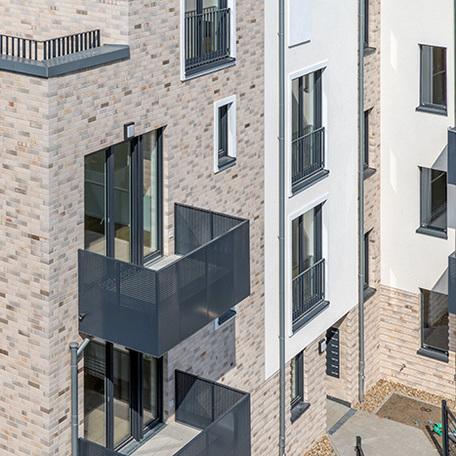 Drohnenansicht eines Wohngebaeudes in Krefeld mit Fokus auf einen Balkon mit Eingang und beiger Fassade