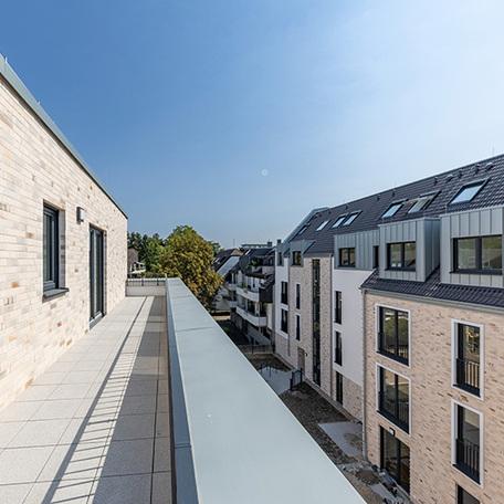 Ausblick von einer Dachterrasse einer Wohnung der drei Wohngebaeude in Krefeld mit beiger Fassade und grauem Dach