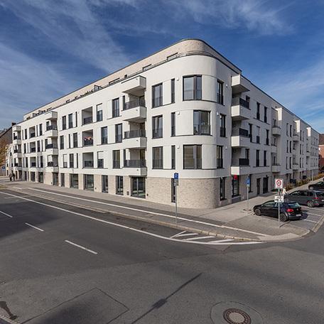 Wohnungen des Wohnquatiers in Moers mit beige, weisser Fassade, Dachterrassen, Balkonen, Parkplaetzen und Strassenanbingung