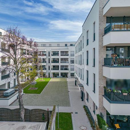 Wohnungen des Wohnquatiers in Moers mit beige, weisser Fassade, Dachterrassen, Balkonen, Gehwegen und Innenhof