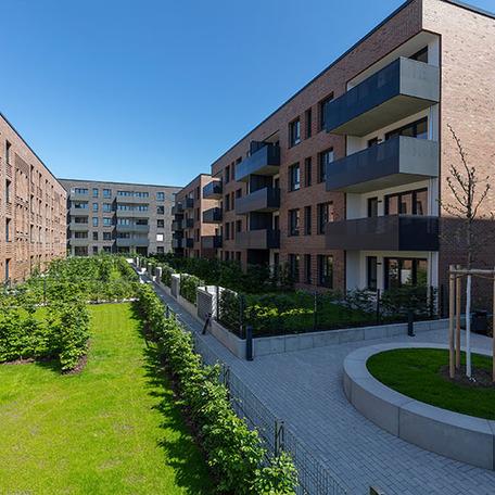 Haeuserreihen im Innenhof des Wohnquatiers in Muenster mit brauner und dunkler Klinkerfassade, Balkonen, Terrassen, Gaerten, Gehwegen und angelegten Beeten