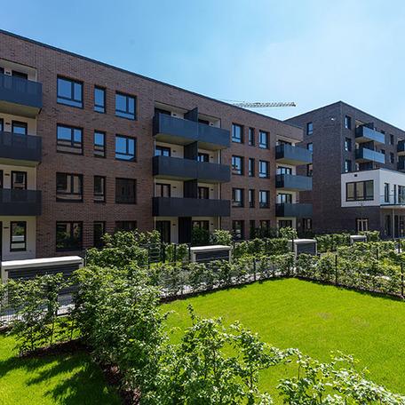 Haeuserreihen des Wohnquatiers in Muenster mit brauner Klinkerfassade, Balkonen, Terrassen, Gaerten und Gehwegen