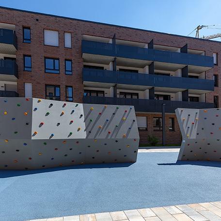 Haeuserreihe des Wohnquatiers in Muenster mit dunkler Klinkerfassade, Balkonen und den Fokus auf die direkt anliegenden Kletterwaende zur sportlichen Betätigung
