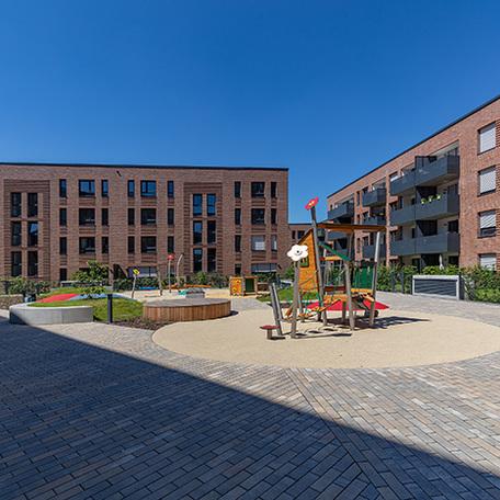 Haeuserreihen des Wohnquatiers in Muenster mit brauner Klinkerfassade, Balkonen und dem Fokus auf den Spielplatz