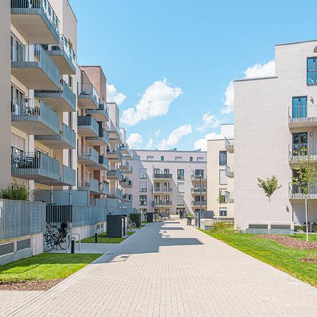 Haeuserreihen des Wohnquatiers in Braunschweig mit heller Fassade, Balkonen, Eingaengen, Gehwegen und angelegten Beeten