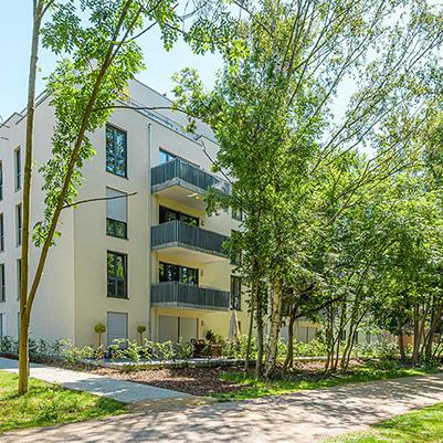 Haeuserreihe des Wohnquatiers in Braunschweig mit heller Fassade, Balkonen, Gehwegen und angelegten Beeten