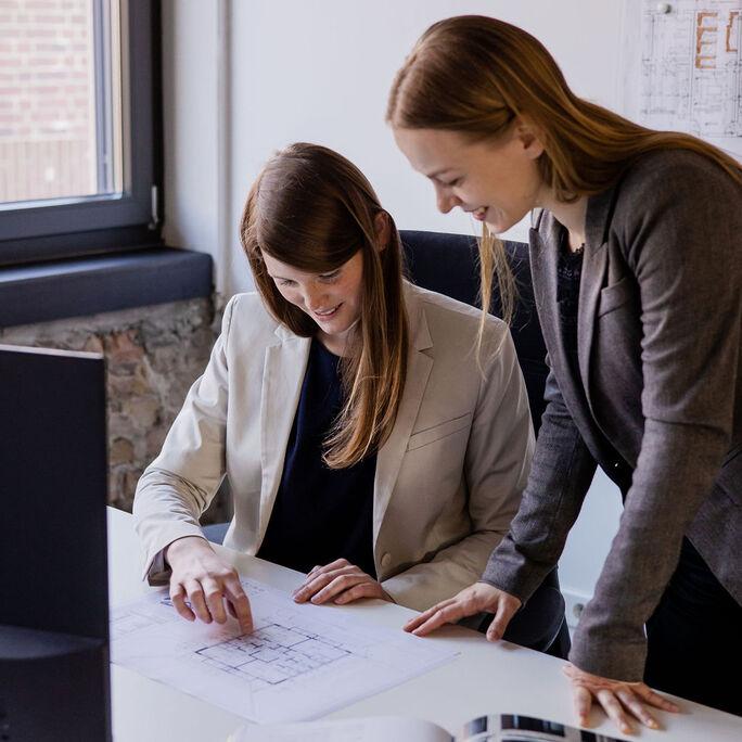 mitarbeiterinnen_besprechung_eines_bauplan_im_buero_schmeing