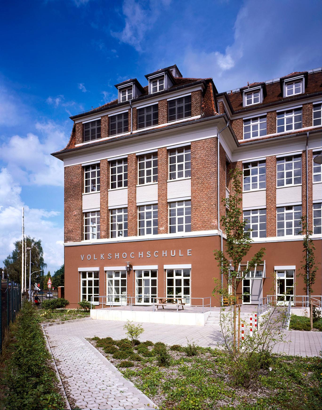 Fokus auf einen Teil des Gebaeudes der Volkshochschule in Nordhorn mit Klinkerfassade, angelegten Beeten, Fenstern und Gehwegen