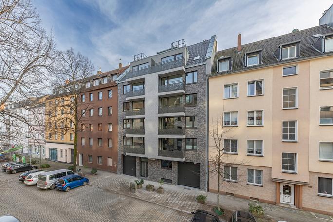 Drohnenaufnahme des Wohngebaeude in Duesseldorf Lindenstrasse von der Strasse aus mit grauer Fassade, Balkonen, Eingangstuer und Einfahrten